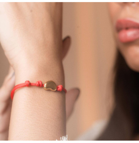 Pulsera de hilo rojo con dije habichuela dorada.